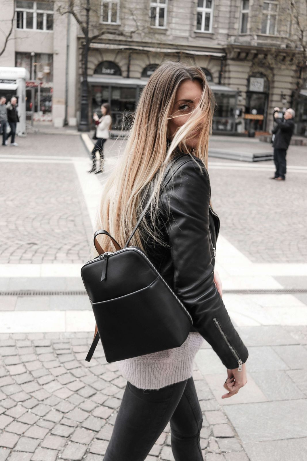 Black leather backpack worn on one shoulder